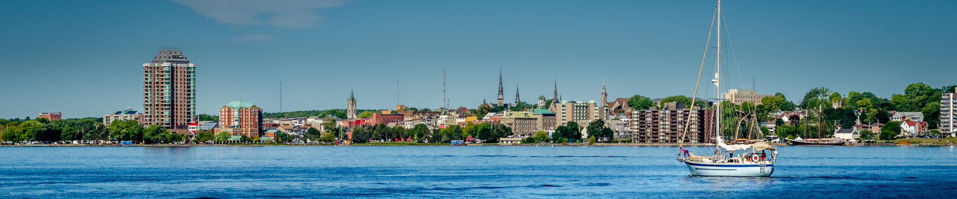 Brockville skyline as seen from the river, with a sailboat moored in the river in the foreground